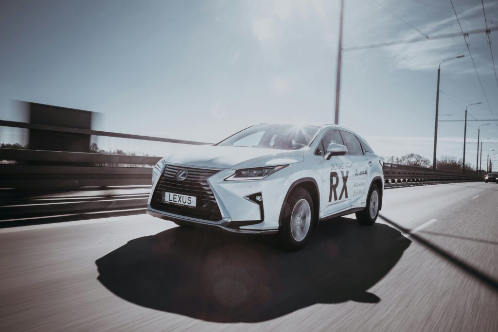Dynamic shot of a white Lexus RX cruising on an open highway under a clear sky.