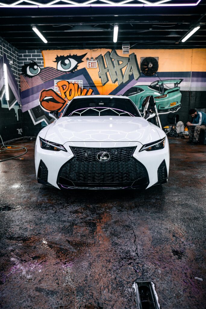 A sleek white Lexus parked in a vibrant urban setting with bold graffiti art in New York.